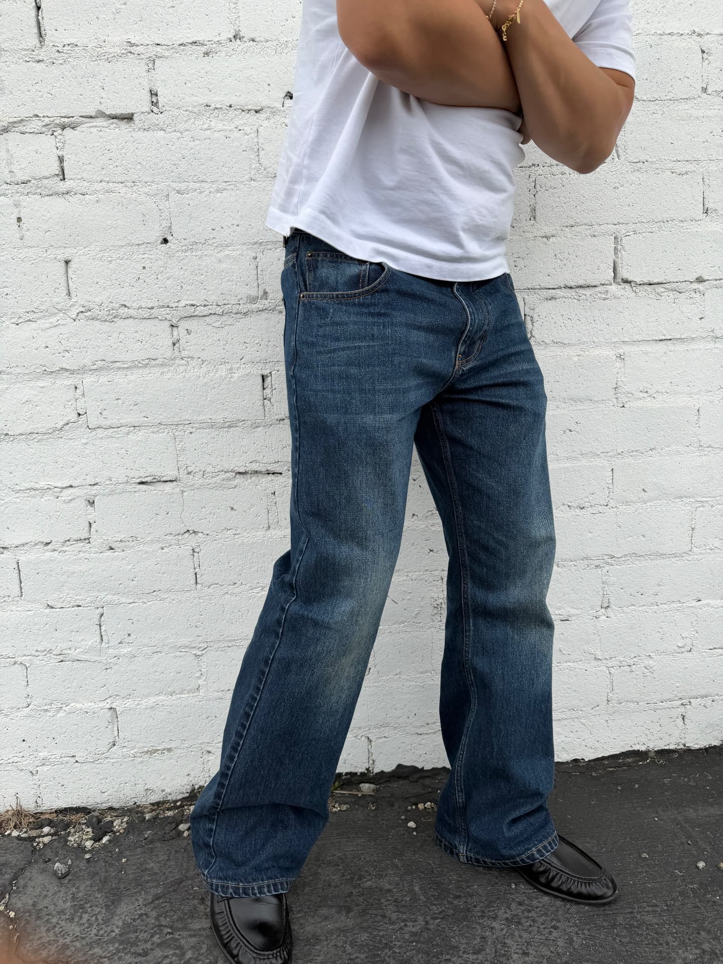 Model wearing Jireh selvedge denim against a white brick wall
